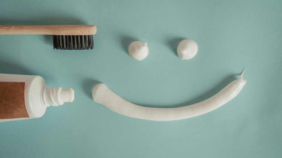 a toothbrush and toothpaste lay next to a smiley face made out of toothpaste
